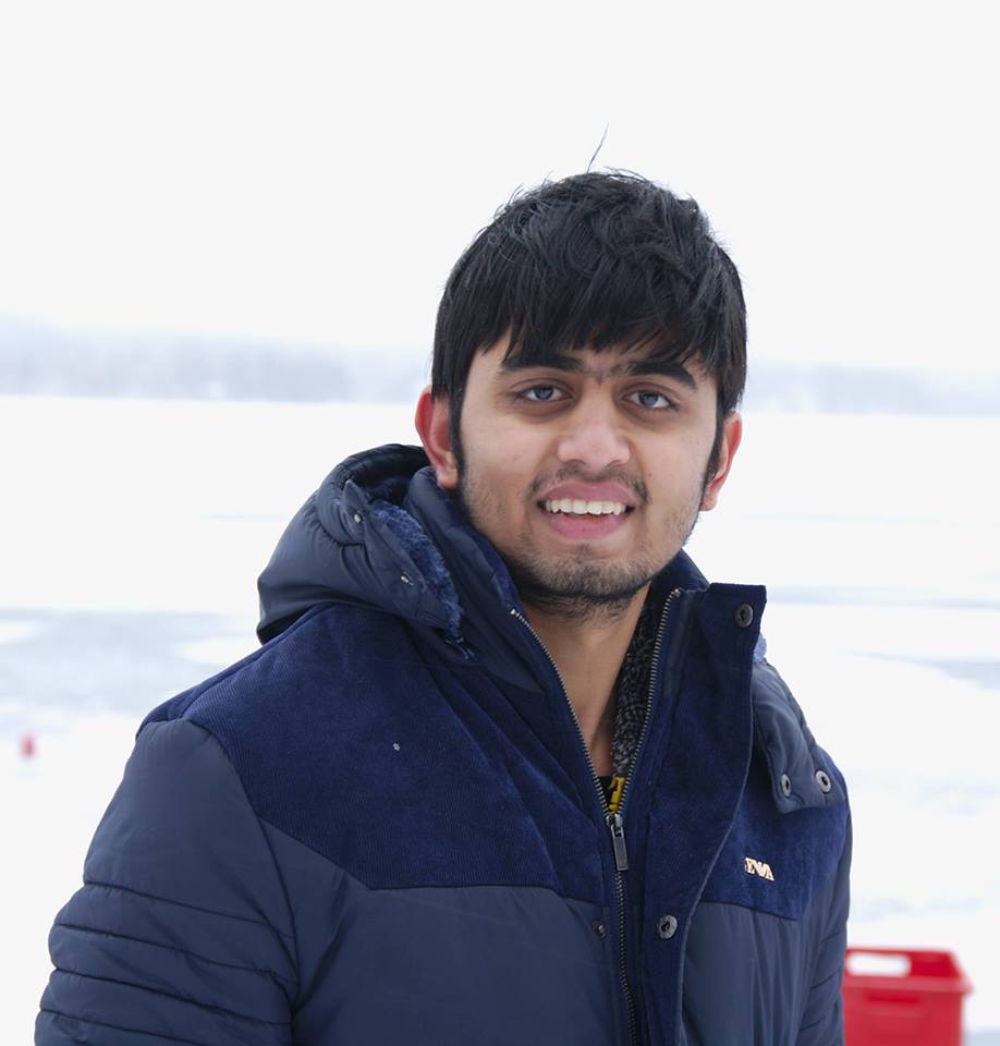 A young Indian man with long bangs wearing a blue winter jacket