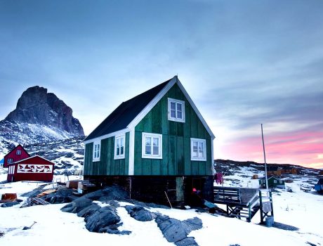 Landscape photo from Greenland with house in foreground and mountain in background.