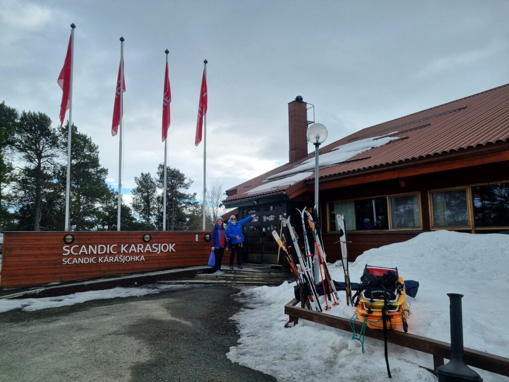 brunt trebygg, ski foran hus, flaggstenger med flagg oppreist utenfor
